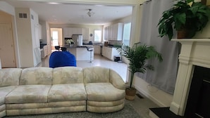 Ein Wohnzimmer mit einem großen, beige-farbenen Ecksofa, einem Kamin und einem Blumentopf.