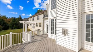 Ein zweistöckiges Haus mit überdachter Veranda und einem umzäunten Deck.
