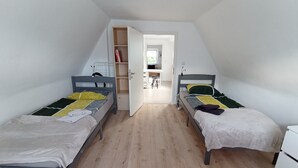 A small, well-lit room with two single beds, a wooden floor, and a white wardrobe. - Cozy Attic Apartment on Großensee - Relaxation at the Gates of Hamburg (Grossensee)