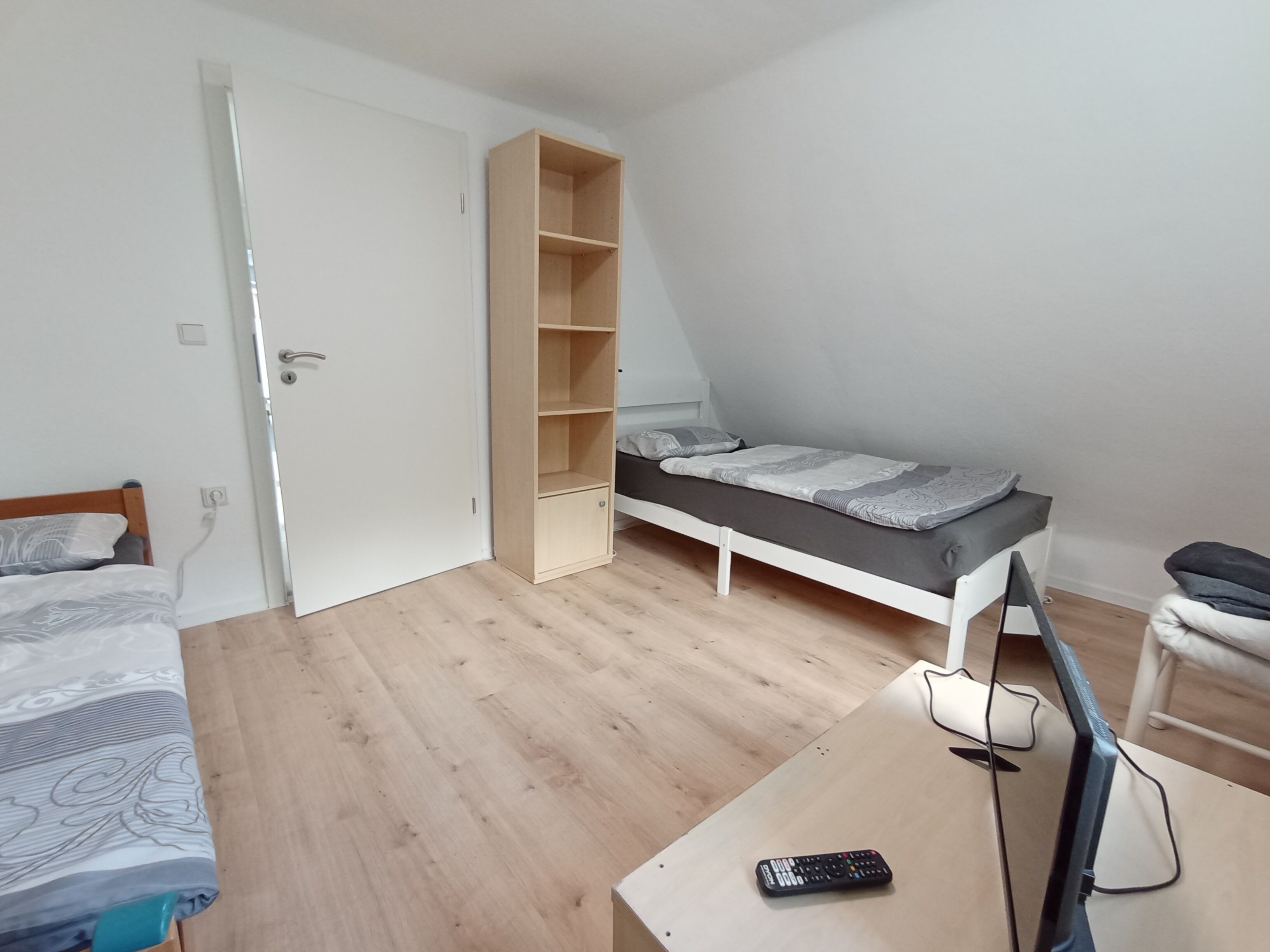 Una stanza piccola e ben illuminata con un letto, una scrivania con un computer e una televisione.