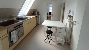 A compact kitchen with a skylight, a small dining table, and a compact refrigerator. - Cozy Attic Apartment on Großensee - Relaxation at the Gates of Hamburg (Grossensee)