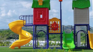 Un parque infantil con un tobogán en espiral amarillo, una estructura de escalada roja y un tobogán verde.
