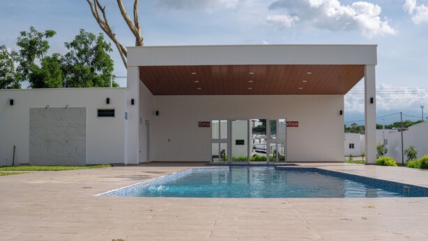 Un área de piscina moderna al aire libre, con una zona de estar cubierta y vistas despejadas a la piscina.