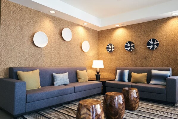 A modern living room with two sofas, a patterned wall, and decorative wall art.