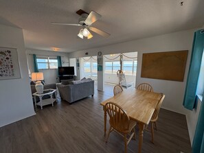 A living room with a sofa, TV, and a dining table with chairs.