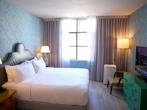 A hotel room with a large bed, a television, a desk with a lamp, and a window with curtains. - Victorian Unit with Pool Access, Fireplace & Free Breakfast in SF SoMa (San Francisco)