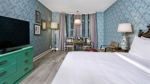 A hotel room with a large bed, a green dresser, a TV, a desk with chairs, and a vase. - Stylish Room with Pool Access, Fireplace & Free Breakfast in San Francisco (San Francisco)