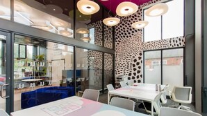 A modern conference room with glass walls, a patterned wall, and a ceiling with circular light fixtures.