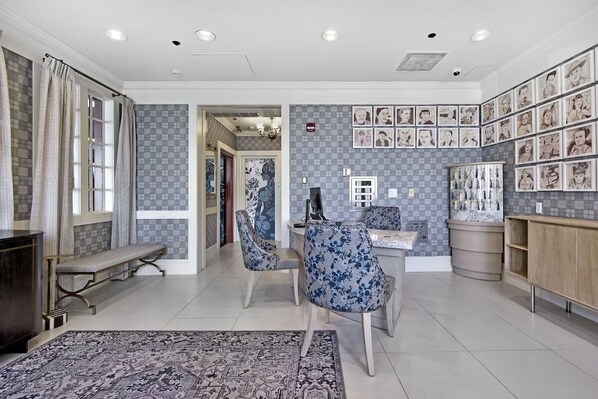 Un salon spacieux avec un grand tapis, deux fauteuils bleus à motifs floraux, un banc et une table basse.