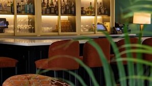 Eine Bar mit einer Glaskühllogbox voller Flaschen, einer Bar und roten Sitzmöglichkeiten.