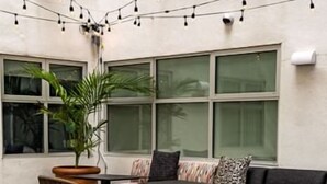 A cozy outdoor seating area with a checkered floor, a wooden table, and string lights. - Unwind in Style at Your Boutique SF Room Near Attractions (San Francisco)