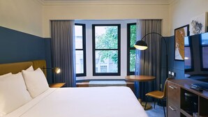 Una habitación de hotel con una cama grande, un escritorio, una silla y un televisor.