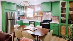 A modern kitchen with green cabinets, stainless steel appliances, and a wooden dining table. - Uptown Peach ~Best 4 Baylor games/visits ~Sleeps 5 (Waco)