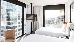 Een hotelkamer met een groot raam, een flatscreen televisie, een bed, een stoel en een bureau.