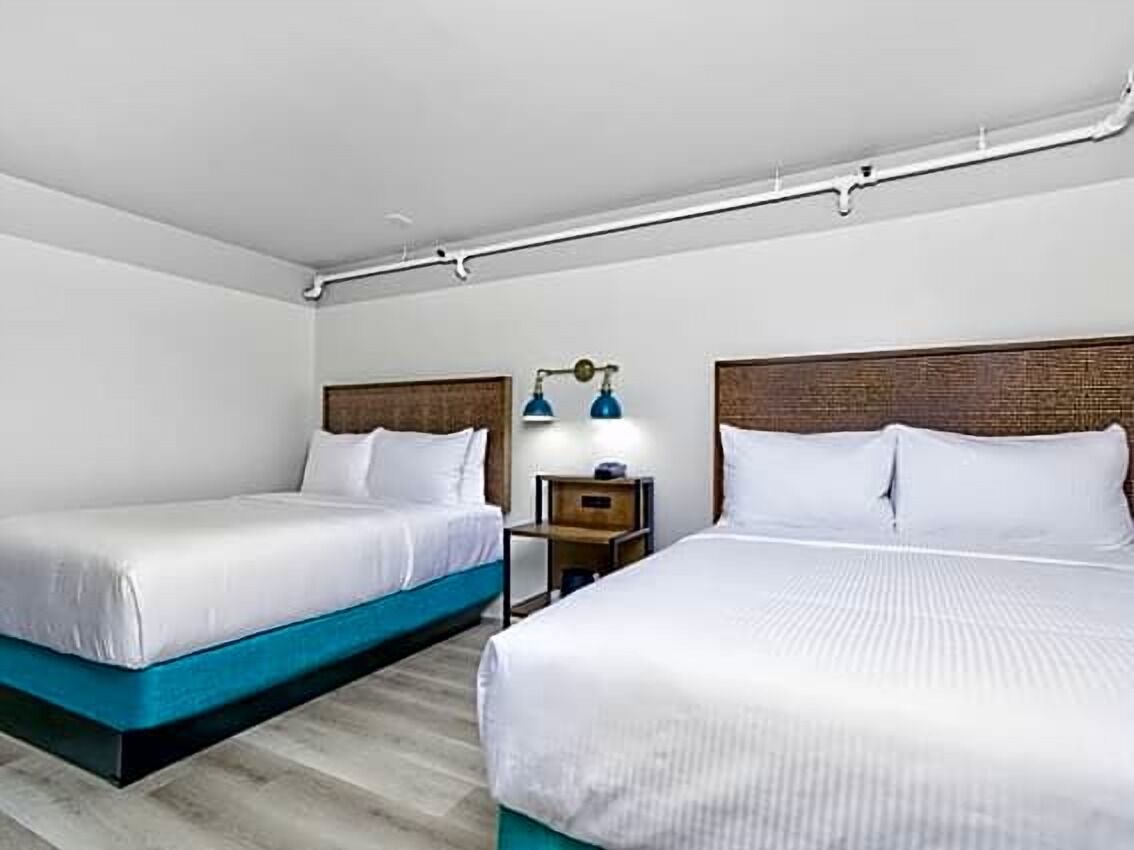 Ett hotellrum med två sängar, ett nattduksbord och en lampa.