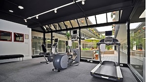 A modern gym with cardio equipment, a bench, and large windows offering views of the outdoors. - 2 Stylish Units with Heated Rooftop Pools, Walk to SF Attractions (San Francisco)