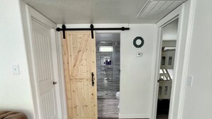 A hallway with a wooden sliding door leading to a bathroom.