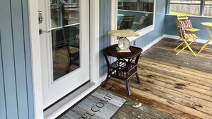 A covered porch with a welcome mat, a scale, and outdoor furniture.