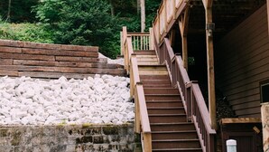 Una escalera de madera que lleva a un edificio con un muro de contención de piedra y un área de grava delante.