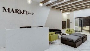 Una moderna zona de recepción con un mostrador blanco, asientos verdes y negros, y suelo de mármol.