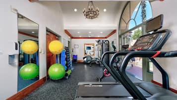 Un gimnasio con cintas de correr, pelotas de ejercicio y un espejo.