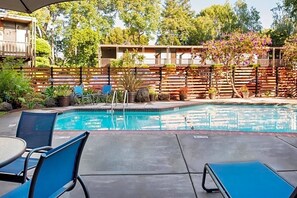 A swimming pool with lounge chairs and a wooden fence in the background. - Eco-Friendly Unit with Outdoor Heated Pool, Free Breakfast & Parking (Palo Alto)