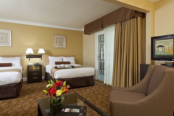 A hotel room with two beds, a television, a coffee table with a vase of flowers, and a view of the outdoors through a window. - Eco-Friendly Unit with Outdoor Heated Pool, Free Breakfast & Parking (Palo Alto)