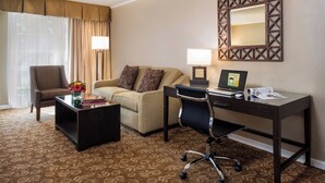 Une chambre d’hôtel équipée d’un canapé, d’un fauteuil, d’un bureau et d’un ordinateur portable.