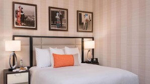 Una habitación de hotel con una cama grande, dos mesitas de noche y tres cuadros en la pared.