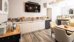 A modern kitchen with a flat-screen TV, a buffet with various food items, and a dining area with chairs and a table. - Beautiful Boutique Room with Breakfast, Near Fisherman’s Wharf & Golden Gate (San Francisco)
