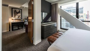 Une chambre d’hôtel avec un lit, un bureau équipé d’un ordinateur, une télévision et une vue sur la ville.