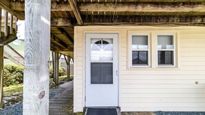 A wooden deck leading to a white door with a window above it.