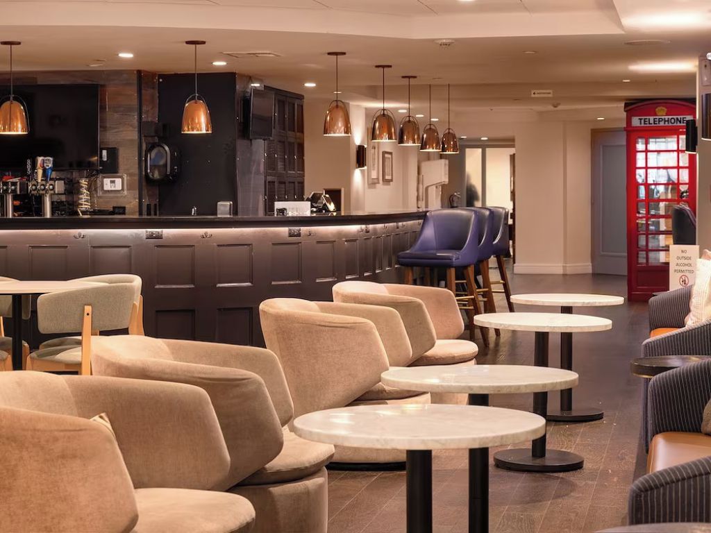 A modern bar area with seating and a red telephone booth.