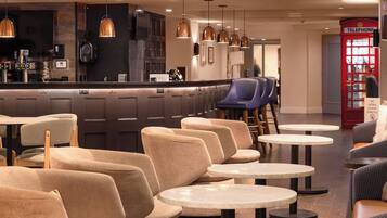 A modern bar area with seating and a red telephone booth.