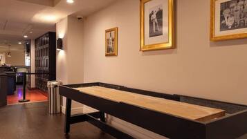 A hallway with framed photographs on the wall, a long wooden bench, and a trash can.