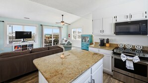 A modern kitchen with granite countertops, white cabinets, a microwave, and an oven.