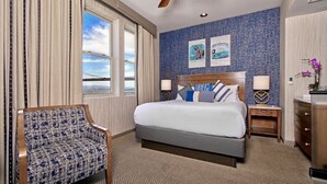 Une chambre d’hôtel avec un grand lit, une chaise, une table de chevet et une commode.
