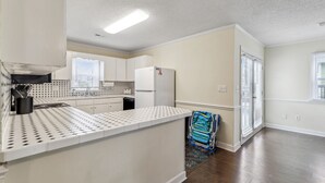 A kitchen with white cabinets, a white countertop, and a refrigerator.