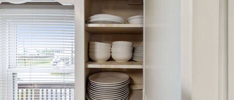 A white cabinet with shelves holding plates and bowls.