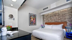 A modern hotel room with a large bed, a wooden headboard, a black countertop with a mirror, and a brick accent wall. - European Room Near Ghirardelli Square, Civic Center & Ferry Terminal (San Francisco)