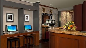 A hotel lobby with a reception desk, two monitors, a coffee machine, and a flower arrangement. - Boutique Unit Near Ferry Building, Powell BART & SFMOMA (San Francisco)