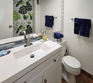 A bathroom with a white sink, a mirror, a toilet, and blue towels hanging on the wall. - Free parking, Partial ocean view, 18th FL, Renovated (Honolulu)