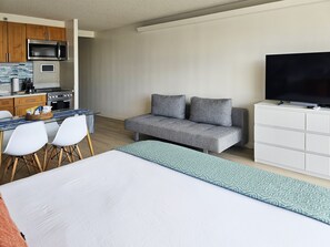 A modern hotel room with a kitchenette, a sofa, a TV, and a bed. - Free parking, Partial ocean view, 18th FL, Renovated (Honolulu)
