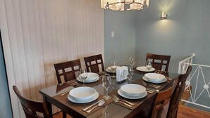 Een eetruimte met een rechthoekige tafel gedekt voor zes personen, omringd door houten stoelen.