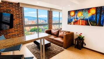 A modern living room with a large window, a brown leather sofa, a dining area with a granite table, and a painting on the wall.