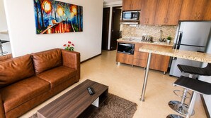 Una sala de estar con un sofá de cuero marrón, una mesa de centro de madera y un cuadro en la pared.