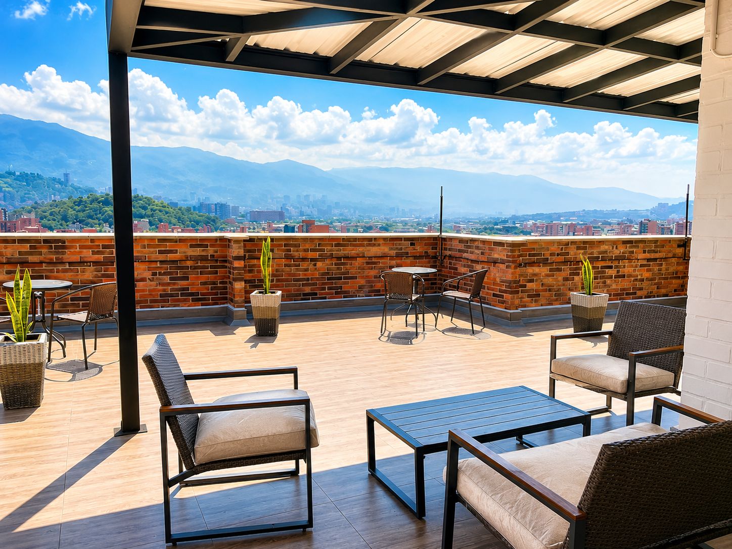 A rooftop patio with seating and potted plants, overlooking a cityscape and mountains.