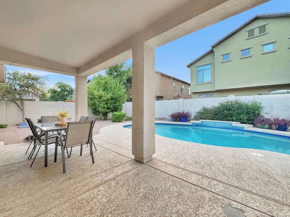 A covered patio area with a pool, outdoor furniture, and a view of neighboring buildings. - 3BR w pool, near MLB spring training (Mesa)