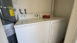 A laundry area with a washing machine and dryer, a water heater, and a red basket on the dryer.