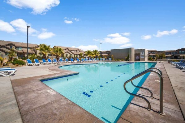 A swimming pool with lounge chairs and a lifeguard stand.